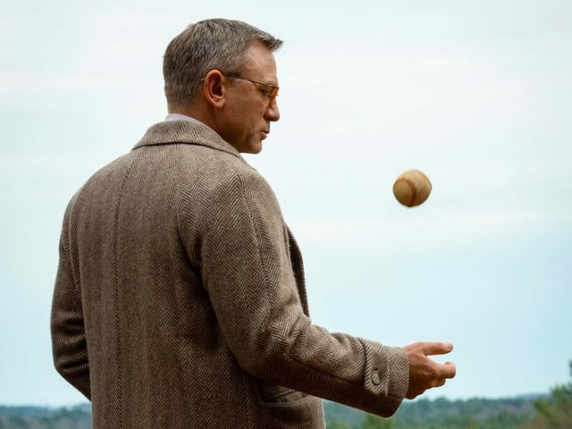 Ein Mann im Mantel spielt mit einem Baseball. Ein Mann im Mantel spielt mit einem Baseball.