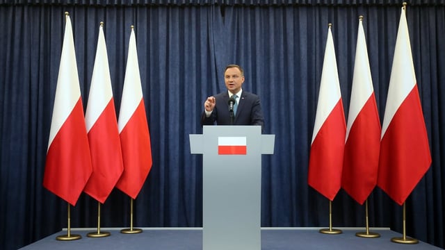 Staatspräsident Andrzej Duda an Rednerpult umrahmt von Polen-Fahnen Staatspräsident Andrzej Duda an Rednerpult umrahmt von Polen-Fahnen