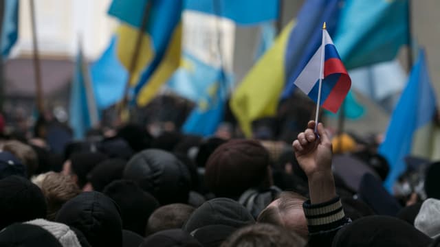 Demonstration in Simferopol vom 26.Februar - viele ukrainische Flaggen im Hintergrund, im Vordergrund streckt ein Demonstrant ein russisches Fähnchen in die Höhe. Demonstration in Simferopol vom 26.Februar - viele ukrainische Flaggen im Hintergrund, im Vordergrund streckt ein Demonstrant ein russisches Fähnchen in die Höhe.