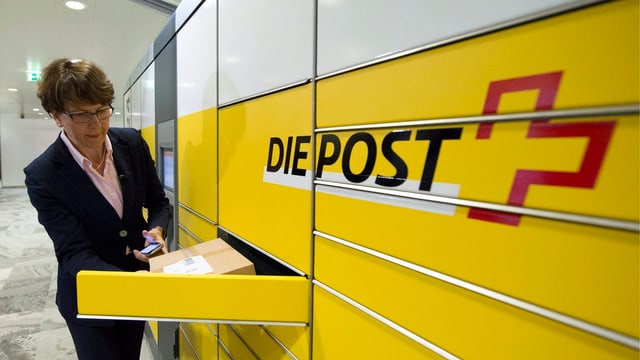 Eine Frau vertaut ein Päckli in einer Schublade, daneben steht gross das Post-Logo. Eine Frau vertaut ein Päckli in einer Schublade, daneben steht gross das Post-Logo.
