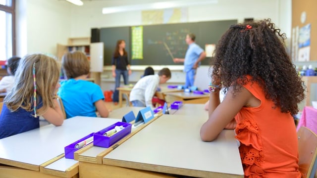 Kinder hören zwei Lehrpersonen zu. Kinder hören zwei Lehrpersonen zu.