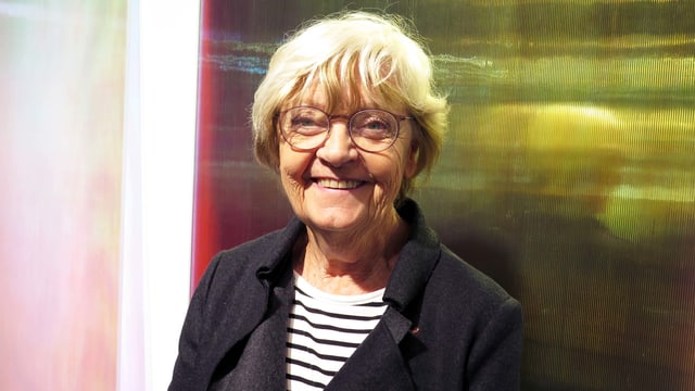 Eine Frau mit Brille vor zwei monochromen Bildern. Eine Frau mit Brille vor zwei monochromen Bildern.