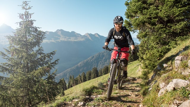 Ein Biker fährt auf einem schmalen Pfad, im Hintergrund sind die Churfirsten abgebildet. Ein Biker fährt auf einem schmalen Pfad, im Hintergrund sind die Churfirsten abgebildet.