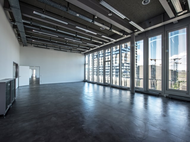 Blick in einen grossen leeren Raum, eine Wand besteht aus einer Fensterfront. Blick in einen grossen leeren Raum, eine Wand besteht aus einer Fensterfront.