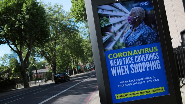 Ein Plakat der englischen Gesundheitsbehörde NHS, das zum Tragen von Hygienemasken auffordert. Ein Plakat der englischen Gesundheitsbehörde NHS, das zum Tragen von Hygienemasken auffordert.