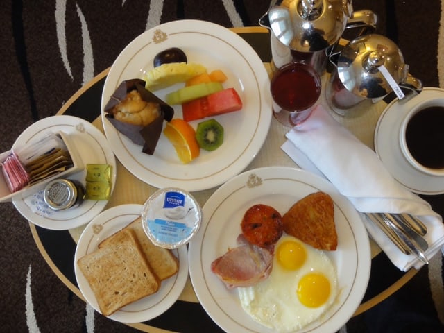 Frühstück auf der Queen Mary 2 mit Spiegelei, Speck, Toast, Früchten und Kaffee.