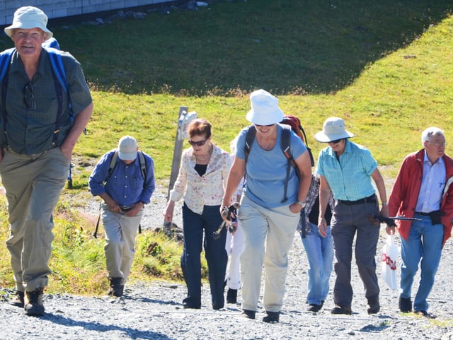 Eine Gruppe von Menschen steigt einen steilen Hang hinauf. Eine Gruppe von Menschen steigt einen steilen Hang hinauf.