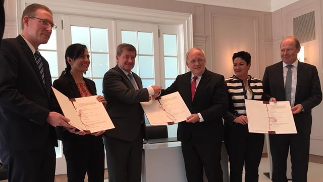 Sechs Personen mit unterschriebenem Dokument. Sechs Personen mit unterschriebenem Dokument.