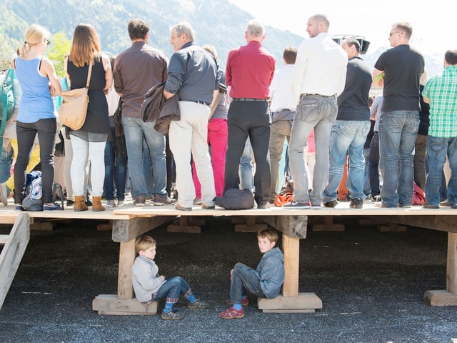 Zwei Jungen an der Landsgemeinde in Glarus sitzen unter einer Tribüne. Zwei Jungen an der Landsgemeinde in Glarus sitzen unter einer Tribüne.