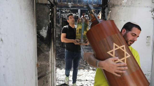 Zwei Männer tragen Thora aus einer Brandruine. Zwei Männer tragen Thora aus einer Brandruine.