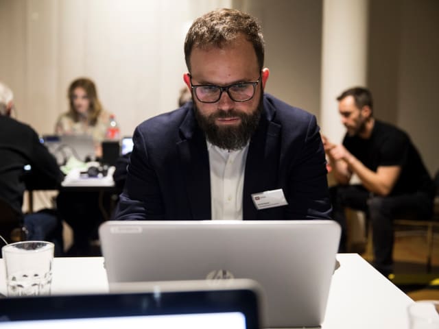 Mann sitzt vor Laptop