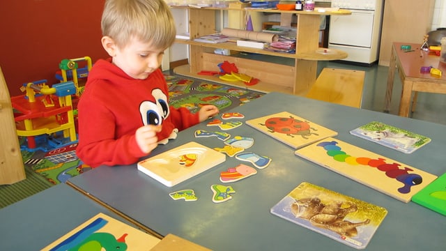 Kind löst Puzzle im Kindergarten Kind löst Puzzle im Kindergarten