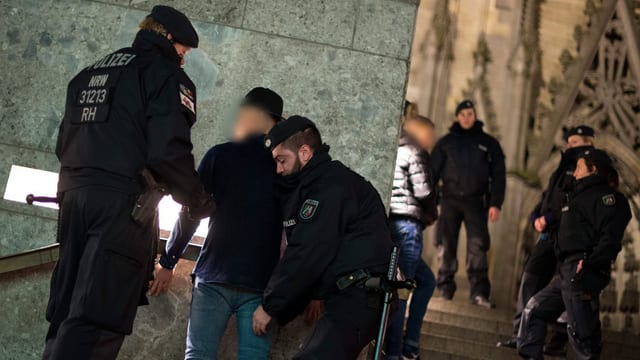 Kölner Polizisten untersuchen Verdächtige vor dem Dom. Kölner Polizisten untersuchen Verdächtige vor dem Dom.