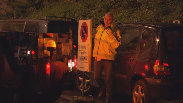 Ein Lastwagen will rückwärts auf einen Parkplatz fahren. Doch ein Auto steht im Weg. Ein Chauffeur steht dazwischen und funkt. Ein Lastwagen will rückwärts auf einen Parkplatz fahren. Doch ein Auto steht im Weg. Ein Chauffeur steht dazwischen und funkt.