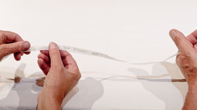 Hände reichen sich einen Papierstreifen weiter. Hände reichen sich einen Papierstreifen weiter.