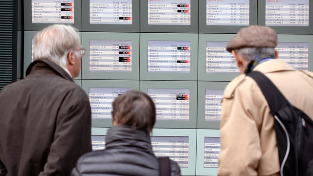 Passanten betrachten Börsenkurse in einem Bank-Schaufenster Passanten betrachten Börsenkurse in einem Bank-Schaufenster