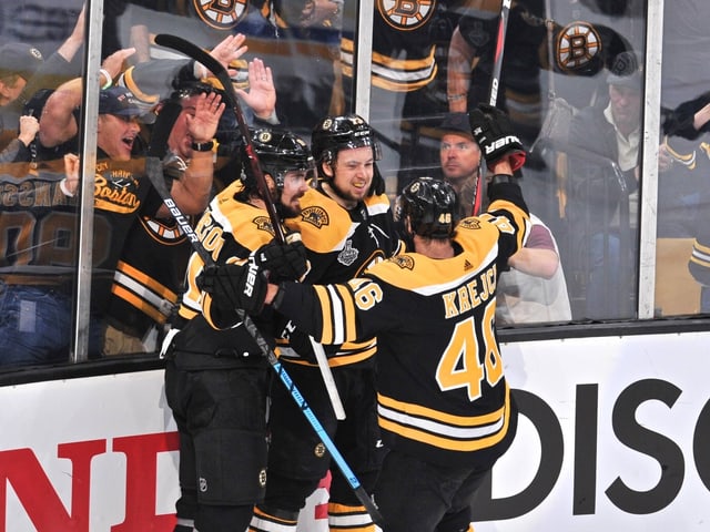 Drei Spieler der Boston Bruins jubeln an der Bande. Drei Spieler der Boston Bruins jubeln an der Bande.