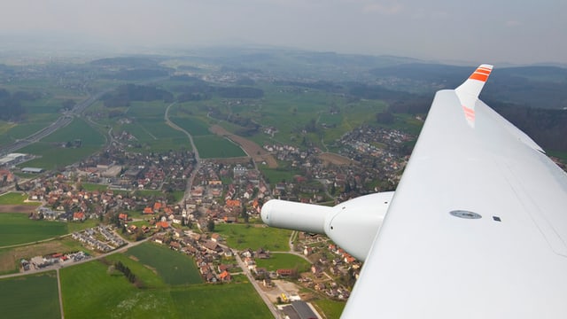 Ein Flügel eines Kleinflugzeugs, darunter eine Siedlung im Mittelland Ein Flügel eines Kleinflugzeugs, darunter eine Siedlung im Mittelland