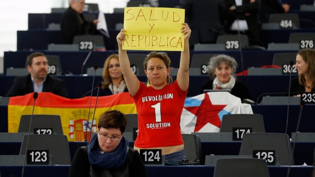Eleonera Forenza hält im EU-Parlament ein Schild hoch. Eleonera Forenza hält im EU-Parlament ein Schild hoch.