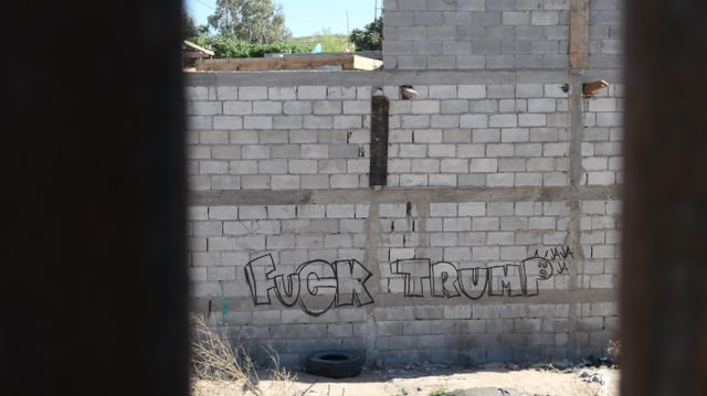 Blick durch den Grenzzaun auf ein Grafitti mit dem Schriftzug: «Fuck Trump». Blick durch den Grenzzaun auf ein Grafitti mit dem Schriftzug: «Fuck Trump».