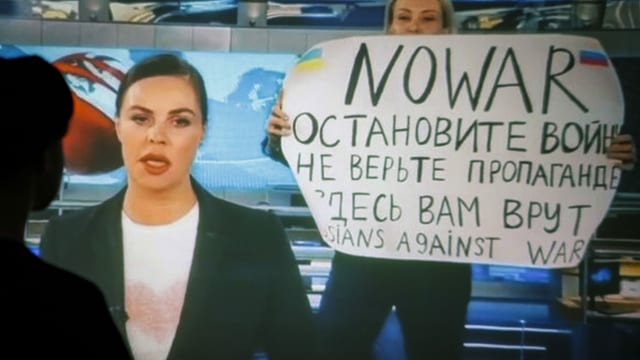 Die Journalistin beim Hochhalten ihres Plakats im Fernsehen.