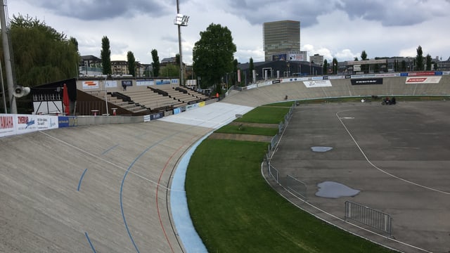 Eine offene Rennbahn, im Hintergrund eine Zuschauertribüne Eine offene Rennbahn, im Hintergrund eine Zuschauertribüne