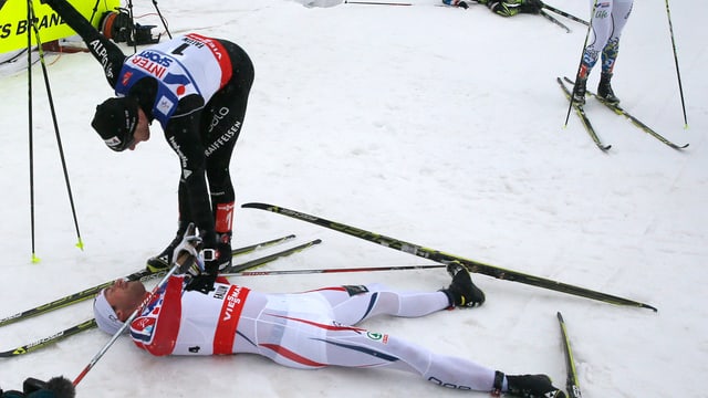 Dario Cologna gratuliert im Zielraum dem neuen völlig ausgepumpten Weltmeister. Dario Cologna gratuliert im Zielraum dem neuen völlig ausgepumpten Weltmeister.
