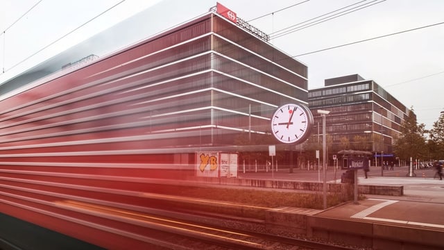 Ein Zug verschwimmt im Bild, hinten ist eine SBB-Uhr zu sehen. Ein Zug verschwimmt im Bild, hinten ist eine SBB-Uhr zu sehen.