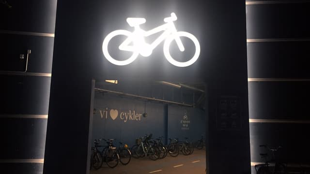 Velokeller bei Nacht. Darüber leuchtet ein Neon-Velo. Velokeller bei Nacht. Darüber leuchtet ein Neon-Velo.