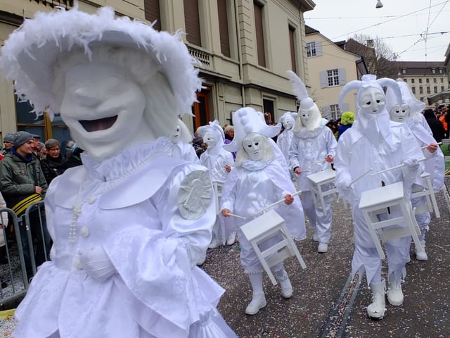 Weisse Larben trommeln auf weissen Stühlen.