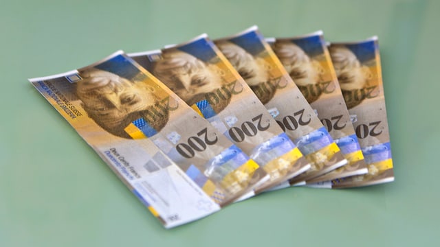 Fünf 200 Franken-Noten aufgefächert auf einem Tisch. Fünf 200 Franken-Noten aufgefächert auf einem Tisch.