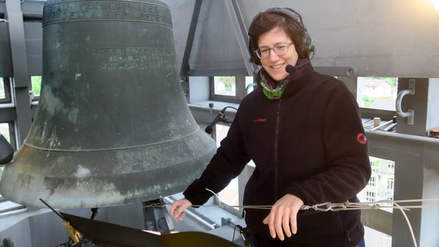 Eine Frau steht neben einer Kirchenglocke Eine Frau steht neben einer Kirchenglocke