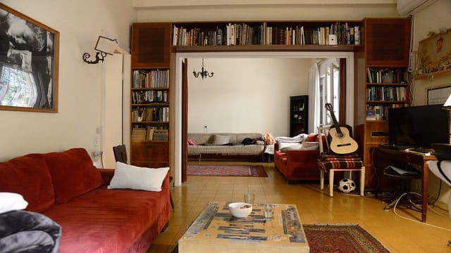 Blick in ein gemütliches Wohnzimmer. Ein rotes Sofa, viele Bücher, ein Stuhl mit einer Gitarre drauf. Blick in ein gemütliches Wohnzimmer. Ein rotes Sofa, viele Bücher, ein Stuhl mit einer Gitarre drauf.