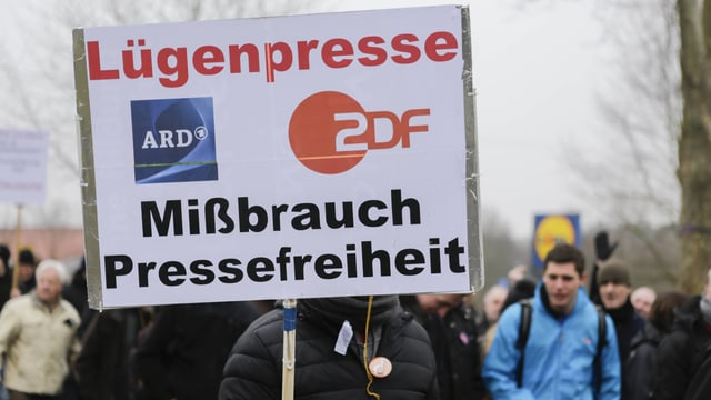 Demonstrant hält ein Schild hoch, auf dem steht: Lügenpresse ARD / ZDF, Missbrauch der Pressefreiheit. Demonstrant hält ein Schild hoch, auf dem steht: Lügenpresse ARD / ZDF, Missbrauch der Pressefreiheit.