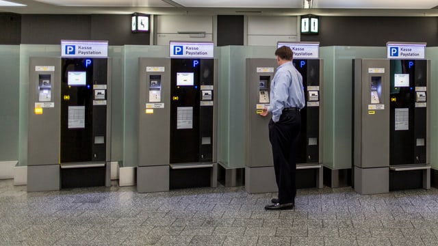 Mann bezahlt an einem Automaten am Flughafen Zürich-Kloten sein Parkhausticket Mann bezahlt an einem Automaten am Flughafen Zürich-Kloten sein Parkhausticket
