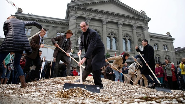 Personen vor dem Bundeshaus, sie schaufeln Fünfräppler. Personen vor dem Bundeshaus, sie schaufeln Fünfräppler.