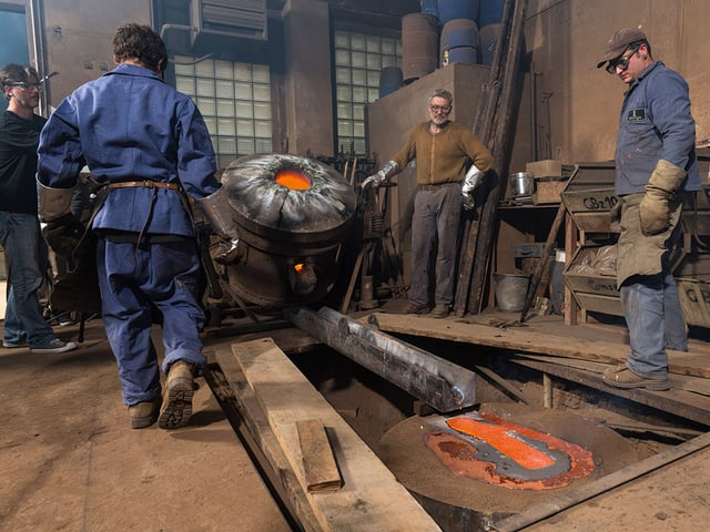 Arbeiter in einer Giesserei, in der demnächst eine Glocke Form annimmt. Arbeiter in einer Giesserei, in der demnächst eine Glocke Form annimmt.