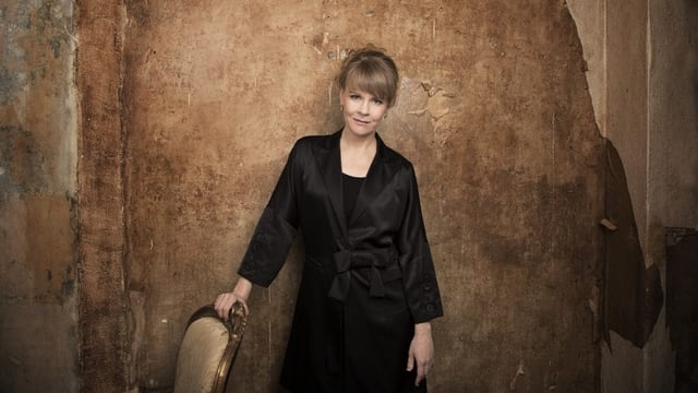 Susanna Mälkki steht vor einer gelb-braunen Wand. Susanna Mälkki steht vor einer gelb-braunen Wand.