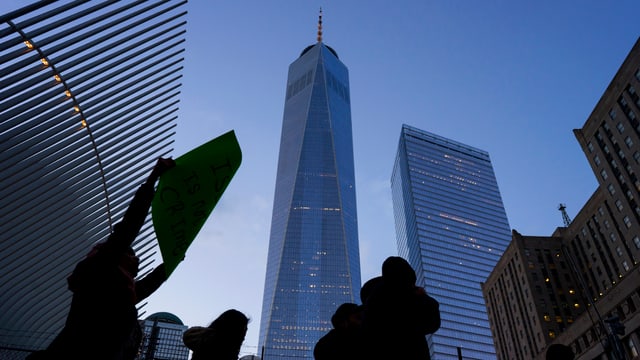 Protestierende Menschen stehen im Gegenlicht vor dem One World Trade Center. Protestierende Menschen stehen im Gegenlicht vor dem One World Trade Center.