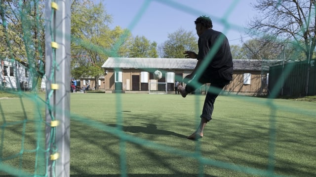 Ein Mann spielt Fussball vor der Asylunterkunft Juch in Zürich. Ein Mann spielt Fussball vor der Asylunterkunft Juch in Zürich.