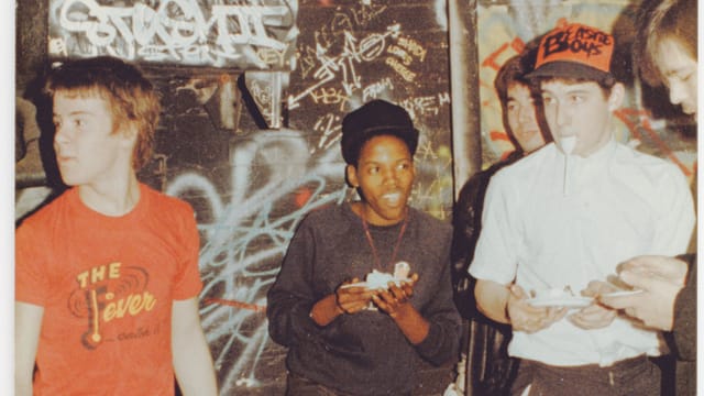 Fünf Buben stehen vor einer besprayten Wand und essen Kuchen. Einer trägt eine Baseballmütze mit der Aufschrift "Beastie Boys". Fünf Buben stehen vor einer besprayten Wand und essen Kuchen. Einer trägt eine Baseballmütze mit der Aufschrift "Beastie Boys".