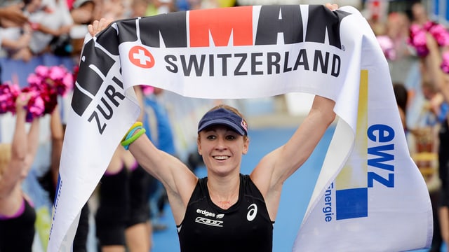 Eine Frau hebt ein Banner mit der Aufschrift Ironman über den Kopf. Eine Frau hebt ein Banner mit der Aufschrift Ironman über den Kopf.