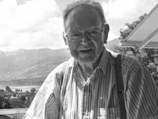 Ein älterer Mann mit Brille vor einem Haus. Ein älterer Mann mit Brille vor einem Haus.