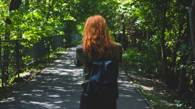 Eine Frau spaziert. Sie ist von hinten fotografiert. Sie hat rote Haare. Eine Frau spaziert. Sie ist von hinten fotografiert. Sie hat rote Haare.