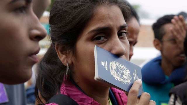 Eine Venezolanerin wartet mit ihrem Pass in der Hand Eine Venezolanerin wartet mit ihrem Pass in der Hand