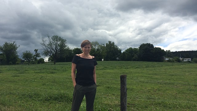 Frau vor einer Wiese mit Wolken am Horizont. Frau vor einer Wiese mit Wolken am Horizont.