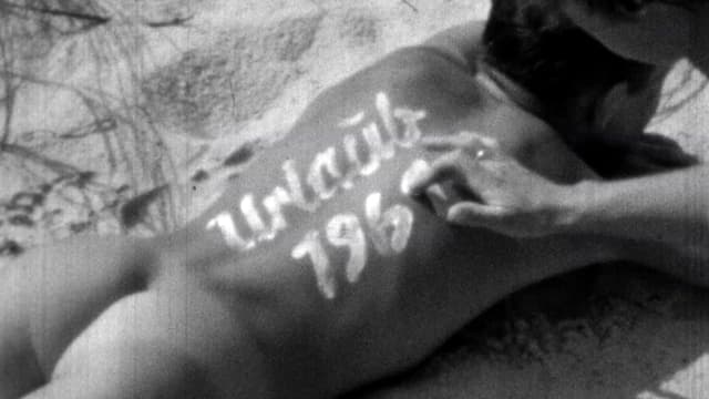 Ein nackten Mann. Auf seinem Rücken steht «Urlaub» mit Sonnencreme. Ein nackten Mann. Auf seinem Rücken steht «Urlaub» mit Sonnencreme.