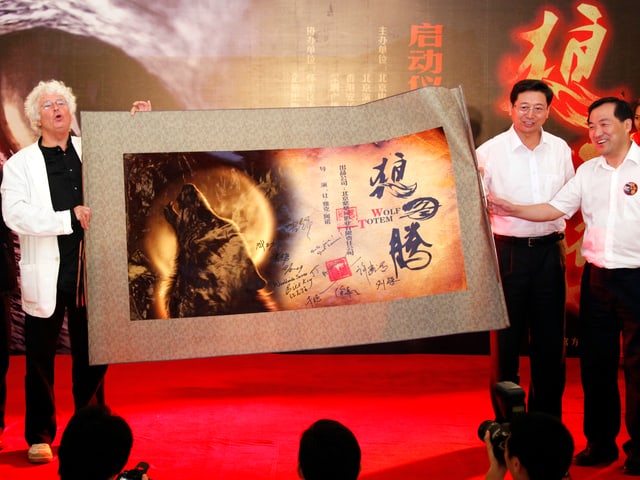 Jean-Jacques Annaud spricht im Rahmen einer Pressekonferenz in Peking vor einem grossen Wolfsauge. Jean-Jacques Annaud spricht im Rahmen einer Pressekonferenz in Peking vor einem grossen Wolfsauge.