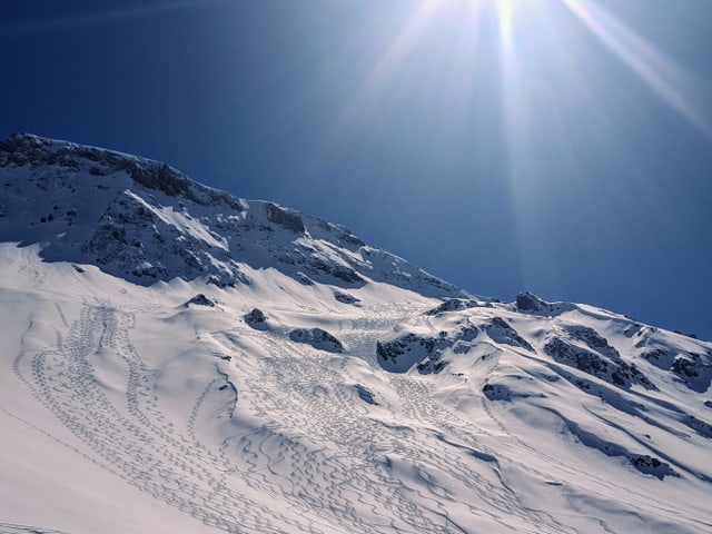 Spuren im Tiefschnee und blauer Himmel.
