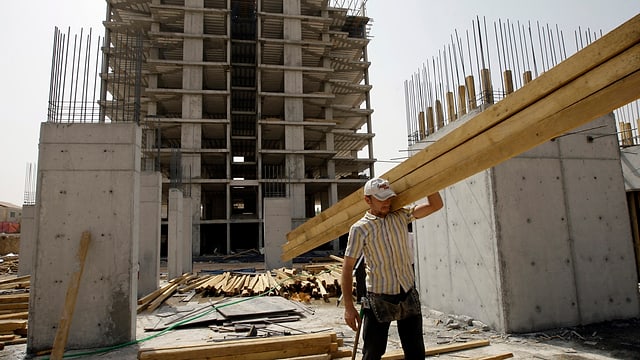 Ein Arbeiter trägt einen grossen Balken über eine der zahlreichen Baustellen in Erbil. Ein Arbeiter trägt einen grossen Balken über eine der zahlreichen Baustellen in Erbil.